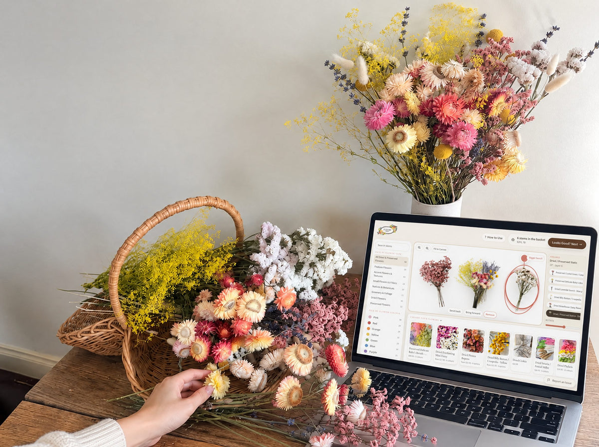 Dried flower arrangement in a wicker basket next to a laptop showing the FLEURI Flower Basket